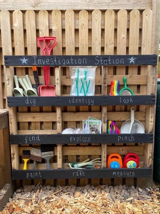 A wooden pallet shelf holding spades, magnifiers, brushes and pots, labelled Investigation Station
