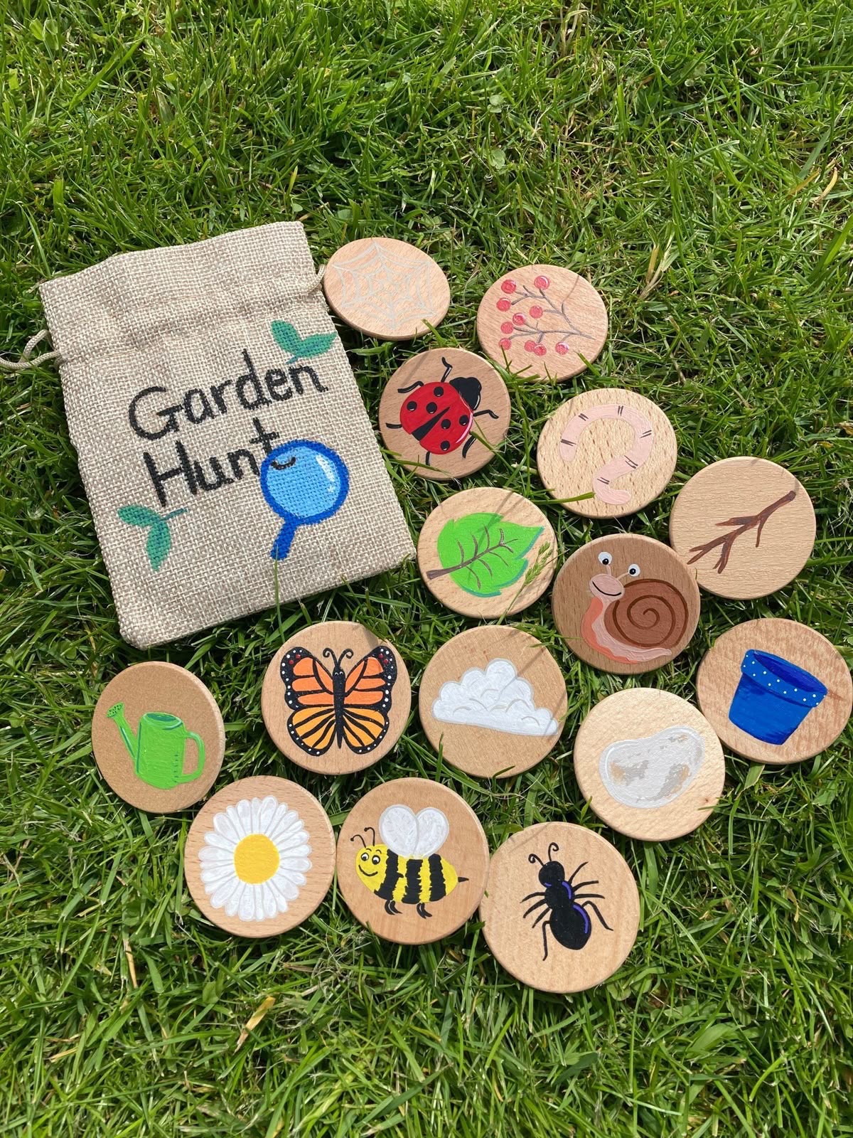 A cloth bag and painted wooden discs showing a ladybird, a bee, a leaf and other garden finds